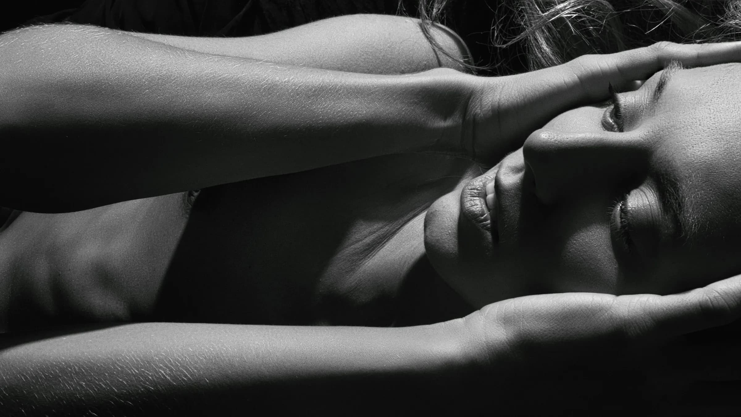 Hände halten ein Gesicht, sinnliche Massage in Schwarzweiss